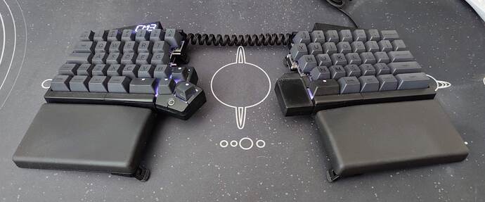 UHK60v2, black case, black palm rests, some modules, SA Black-on-Black keycaps, on a solar system desk mat