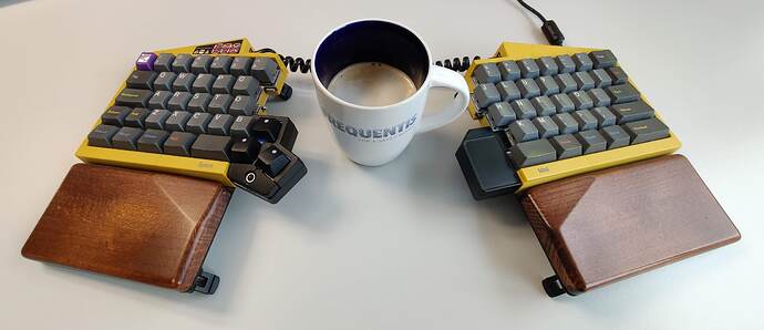 UHK60v1, mustard case, wooden palm rests, some modules, GMK Oblivion v2 keycaps, and a coffee cup